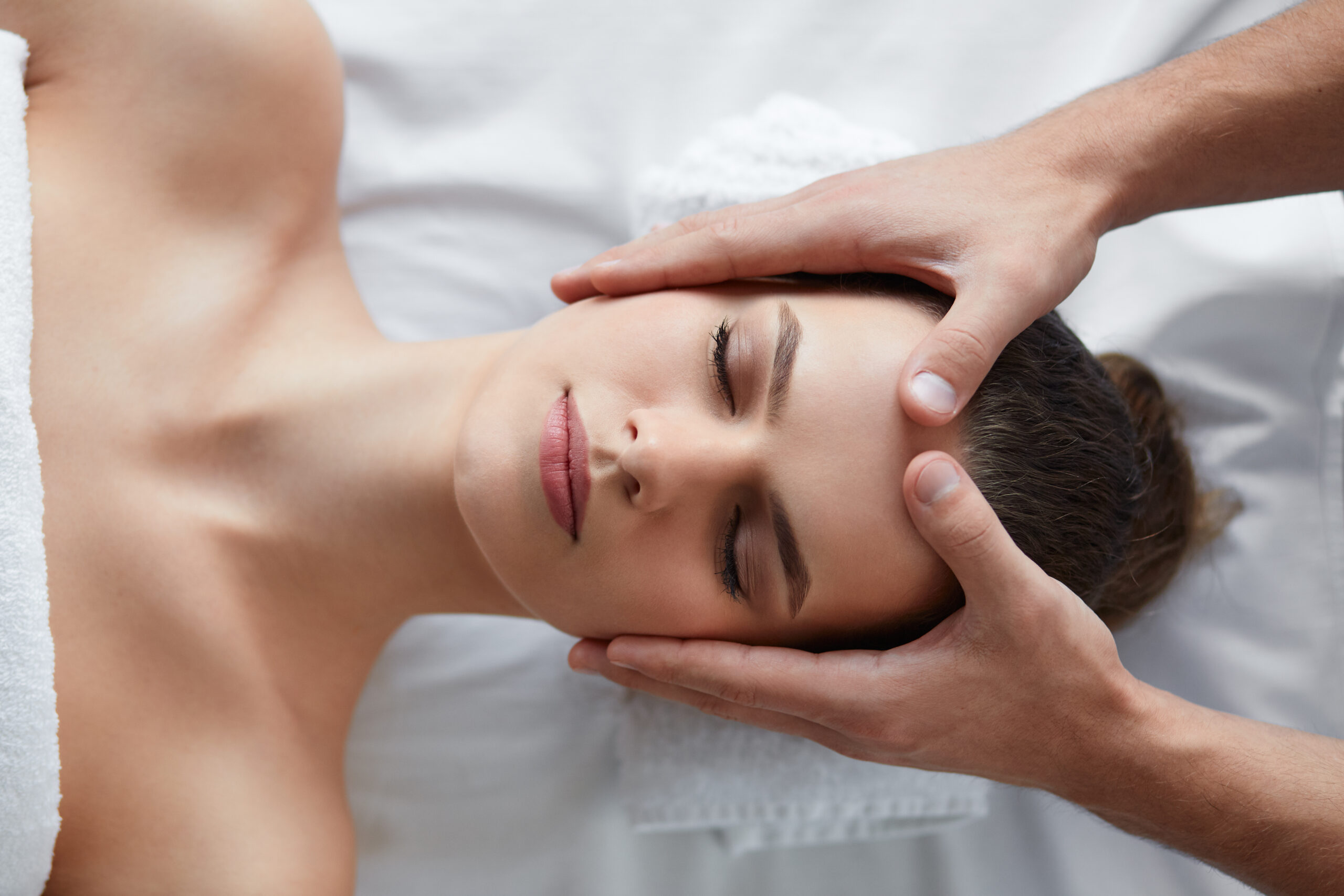 young beautiful woman enjoying anti aging facial massage.male therapist making head massage to female client.professional masseur.relaxation,beauty,spa,body and face treatment concept